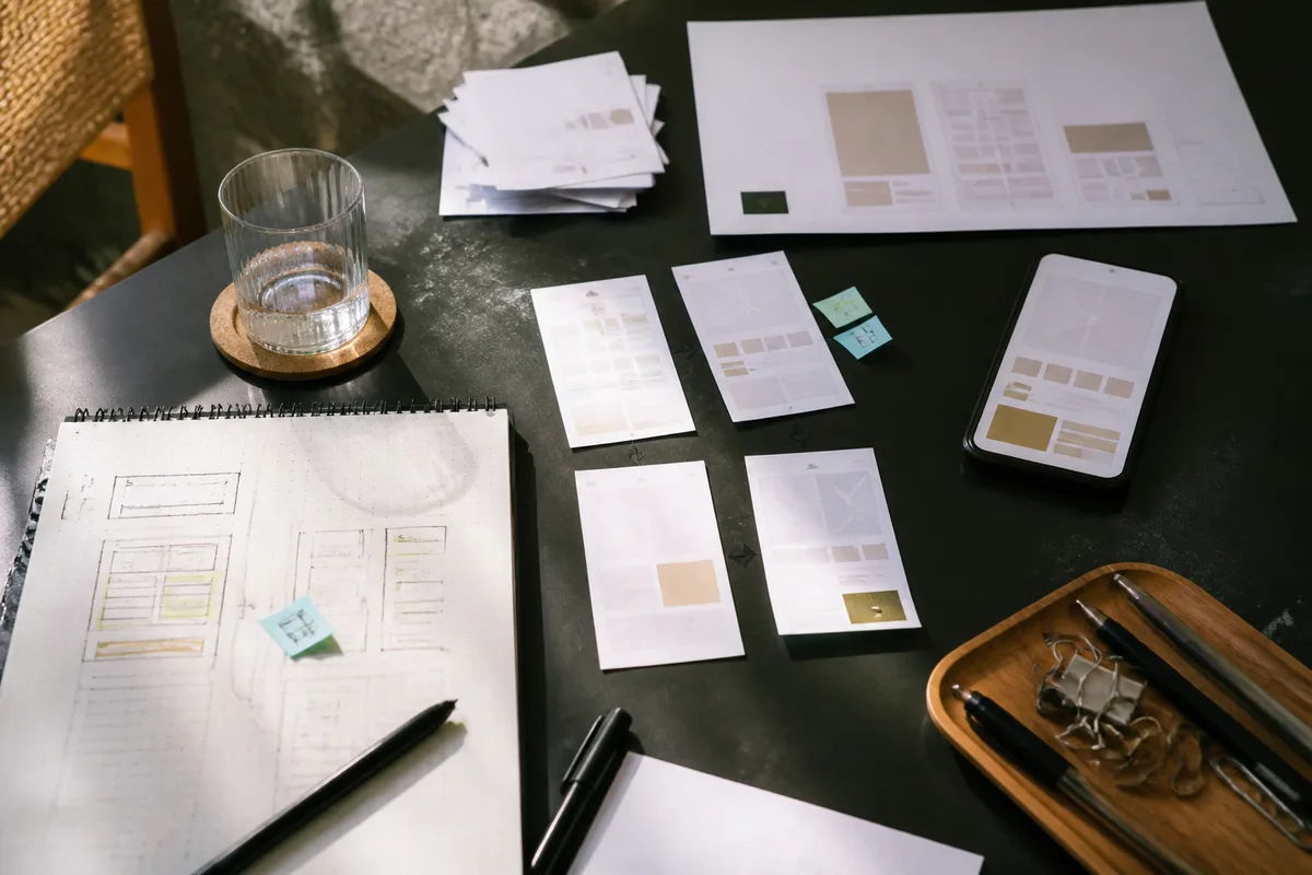 Table de travail avec maquettes papier et outils no-code pour concevoir un service numérique